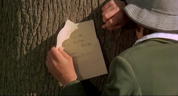 Movie still from “The Go-Between” (1971), directed by Joseph Losey – A person holding an open letter in front of a tree trunk; Close Up shot, Overhead angle