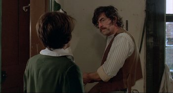 Movie still from “The Go-Between” (1971), directed by Joseph Losey – A man in a striped vest is looking in the mirror; Medium shot, Over the shoulder angle