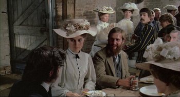Movie still from “The Go-Between” (1971), directed by Joseph Losey – A group of people sitting at a table wearing hats; Medium shot, Over the shoulder angle