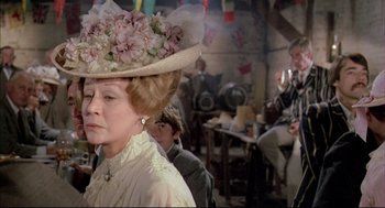Movie still from “The Go-Between” (1971), directed by Joseph Losey – An older woman wearing a hat with pink flowers on it; Close Up shot, Over the shoulder angle