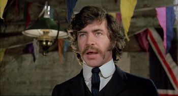 Movie still from “The Go-Between” (1971), directed by Joseph Losey – A person wearing a suit and tie; Close Up shot, Low angle