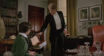 Movie still from “The Go-Between” (1971), directed by Joseph Losey – A man in a tuxedo handing a box to another man; Medium shot, Over the shoulder angle