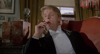 Movie still from “The Go-Between” (1971), directed by Joseph Losey – A man sitting in a chair smoking a cigarette; Close Up shot, Low angle