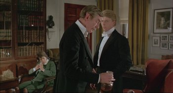 Movie still from “The Go-Between” (1971), directed by Joseph Losey – Two men in tuxedos standing next to each other holding cans; Medium shot, Over the shoulder angle