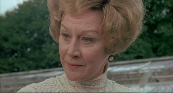 Movie still from “The Go-Between” (1971), directed by Joseph Losey – An older woman in a white dress looking at the camera; Close Up shot, Over the shoulder angle