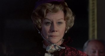 Movie still from “The Go-Between” (1971), directed by Joseph Losey – An older woman wearing a purple hat and a red dress; Close Up shot, Low angle