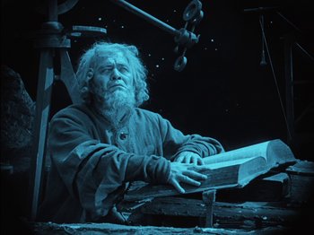 Movie still from “The Golem” (1920), directed by Paul Wegener – An old man sitting in a chair holding a book; Medium shot, Low angle