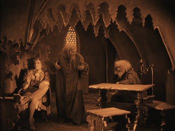 Movie still from “The Golem” (1920), directed by Paul Wegener – A group of people sitting around a table; Wide shot, High angle