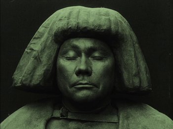 Movie still from “The Golem” (1920), directed by Paul Wegener – A statue of a man wearing a hat; Close Up shot, High angle
