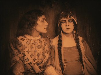Movie still from “The Golem” (1920), directed by Paul Wegener – Two women dressed in medieval garb , one of which is holding a sword; Medium shot, High angle
