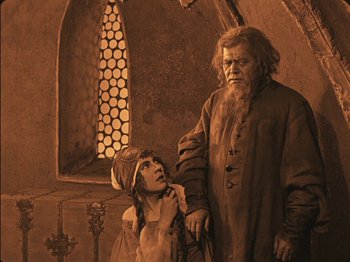 Movie still from “The Golem” (1920), directed by Paul Wegener – A man and a boy standing next to each other in front of a window; Medium shot, High angle