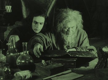 Movie still from “The Golem” (1920), directed by Paul Wegener – A man and a woman sitting at a table with a book; Medium shot, High angle
