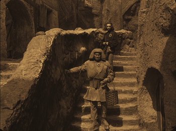 Movie still from “The Golem” (1920), directed by Paul Wegener – Two men in medieval garb standing at the top of a set of stairs; Wide shot, High angle