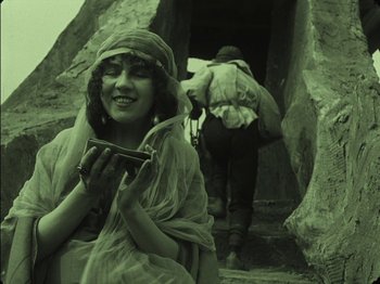 Movie still from “The Golem” (1920), directed by Paul Wegener – An old photo of a woman holding a cell phone; Medium shot, High angle