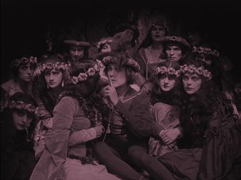 Movie still from “The Golem” (1920), directed by Paul Wegener – A group of people dressed in costumes and wearing flower wreaths on their heads; Wide shot, High angle