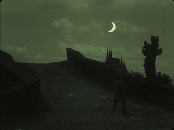 Movie still from “The Golem” (1920), directed by Paul Wegener – A person standing on a hill under a cloudy night sky; Extreme Wide shot, Low angle