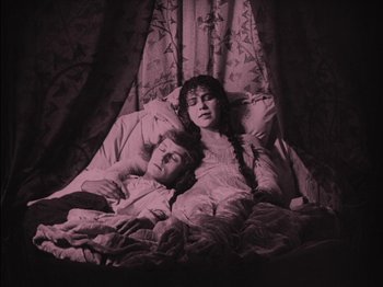 Movie still from “The Golem” (1920), directed by Paul Wegener – A man and a woman laying in bed under a comforter; Medium shot, High angle