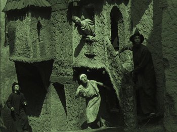 Movie still from “The Golem” (1920), directed by Paul Wegener – A group of people standing next to each other in front of a building; Wide shot, High angle
