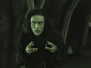 Movie still from “The Golem” (1920), directed by Paul Wegener – A man in a black jacket is looking at the camera; Medium shot, Low angle