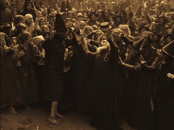Movie still from “The Golem” (1920), directed by Paul Wegener – A group of people dressed up as witches; Wide shot, High angle