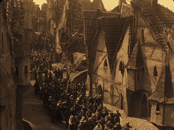 Movie still from “The Golem” (1920), directed by Paul Wegener – A crowd of people walking down a street; Extreme Wide shot, High angle