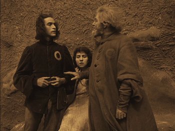 Movie still from “The Golem” (1920), directed by Paul Wegener – A group of people standing next to each other in front of a wall; Medium shot, Low angle