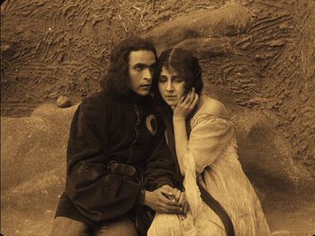 Movie still from “The Golem” (1920), directed by Paul Wegener – A man and a woman sitting next to each other; Medium shot, High angle