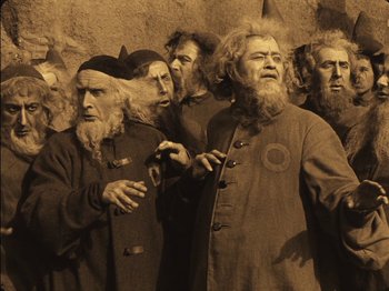 Movie still from “The Golem” (1920), directed by Paul Wegener – A group of men standing next to each other; Medium shot, Low angle