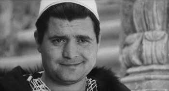 Movie still from “The Gospel According to St. Matthew” (1964), directed by Pier Paolo Pasolini – A black and white photo of a man wearing a hat; Close Up shot, High angle