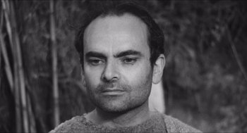 Movie still from “The Gospel According to St. Matthew” (1964), directed by Pier Paolo Pasolini – Black and white photograph of a man in a sweater looking straight ahead; Close Up shot, High angle