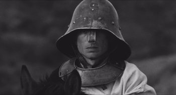 Movie still from “The Gospel According to St. Matthew” (1964), directed by Pier Paolo Pasolini – A man wearing a helmet with a bird on his shoulder; Close Up shot, Low angle