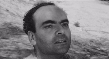 Movie still from “The Gospel According to St. Matthew” (1964), directed by Pier Paolo Pasolini – Black and white photograph of a man in a sweater; Close Up shot, High angle