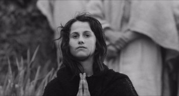 Movie still from “The Gospel According to St. Matthew” (1964), directed by Pier Paolo Pasolini – A woman with long brown hair is praying; Close Up shot, High angle