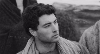 Movie still from “The Gospel According to St. Matthew” (1964), directed by Pier Paolo Pasolini – Black and white photograph of a man with a beard; Close Up shot, Over the shoulder angle