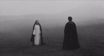 Movie still from “The Gospel According to St. Matthew” (1964), directed by Pier Paolo Pasolini – A man and a woman dressed in robes in a field; Wide shot, Over the shoulder angle