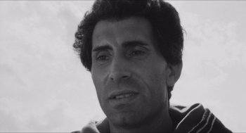 Movie still from “The Gospel According to St. Matthew” (1964), directed by Pier Paolo Pasolini – Black and white photograph of a man looking at the camera; Close Up shot, Low angle