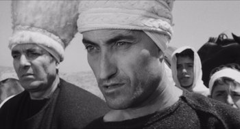 Movie still from “The Gospel According to St. Matthew” (1964), directed by Pier Paolo Pasolini – Black and white photograph of a man wearing a turban; Close Up shot, Low angle