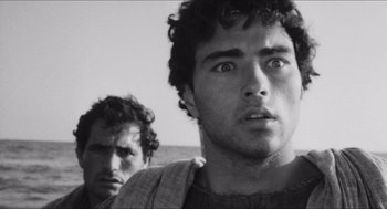 Movie still from “The Gospel According to St. Matthew” (1964), directed by Pier Paolo Pasolini – Two men standing next to each other on a beach; Close Up shot, Over the shoulder angle