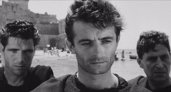 Movie still from “The Gospel According to St. Matthew” (1964), directed by Pier Paolo Pasolini – Black and white photograph of a young man on the beach; Close Up shot, Over the shoulder angle