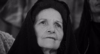 Movie still from “The Gospel According to St. Matthew” (1964), directed by Pier Paolo Pasolini – An older woman with a black veil on her head; Close Up shot, Low angle