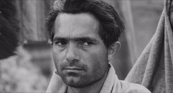 Movie still from “The Gospel According to St. Matthew” (1964), directed by Pier Paolo Pasolini – Black and white photograph of a man looking at the camera; Close Up shot, Low angle
