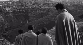 Movie still from “The Gospel According to St. Matthew” (1964), directed by Pier Paolo Pasolini – A black and white photo of a group of people on a hill; Wide shot, High angle