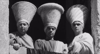 Movie still from “The Gospel According to St. Matthew” (1964), directed by Pier Paolo Pasolini – A group of men standing next to each other wearing hats; Medium shot, Low angle