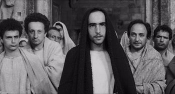 Movie still from “The Gospel According to St. Matthew” (1964), directed by Pier Paolo Pasolini – Black and white photograph of a man in a group of people; Medium shot, Low angle