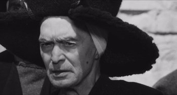 Movie still from “The Gospel According to St. Matthew” (1964), directed by Pier Paolo Pasolini – An old man wearing a hat and looking at the camera; Close Up shot, Low angle