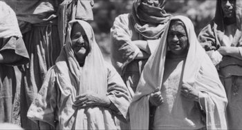 Movie still from “The Gospel According to St. Matthew” (1964), directed by Pier Paolo Pasolini – A black and white photo of two women and a man; Medium shot, High angle