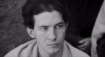 Movie still from “The Gospel According to St. Matthew” (1964), directed by Pier Paolo Pasolini – Black and white photograph of a young man with long dark hair; Close Up shot, High angle