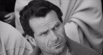 Movie still from “The Gospel According to St. Matthew” (1964), directed by Pier Paolo Pasolini – Black and white photograph of a man looking at the camera; Close Up shot, High angle