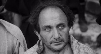 Movie still from “The Gospel According to St. Matthew” (1964), directed by Pier Paolo Pasolini – Black and white photograph of a man looking at the camera; Close Up shot, High angle