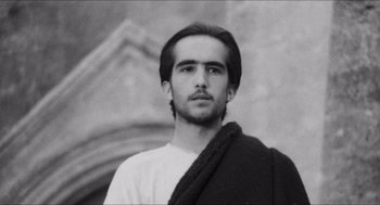 Movie still from “The Gospel According to St. Matthew” (1964), directed by Pier Paolo Pasolini – Black and white photograph of a young man wearing a toga; Close Up shot, Low angle
